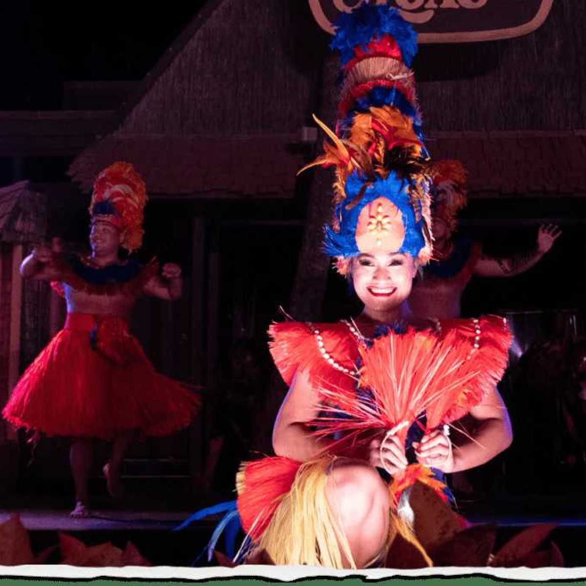 Dancers in vibrant costumes perform on stage under colorful lights.